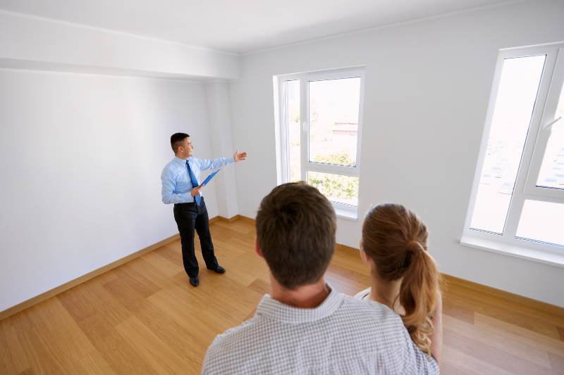 realtor with clipboard and couple at new home