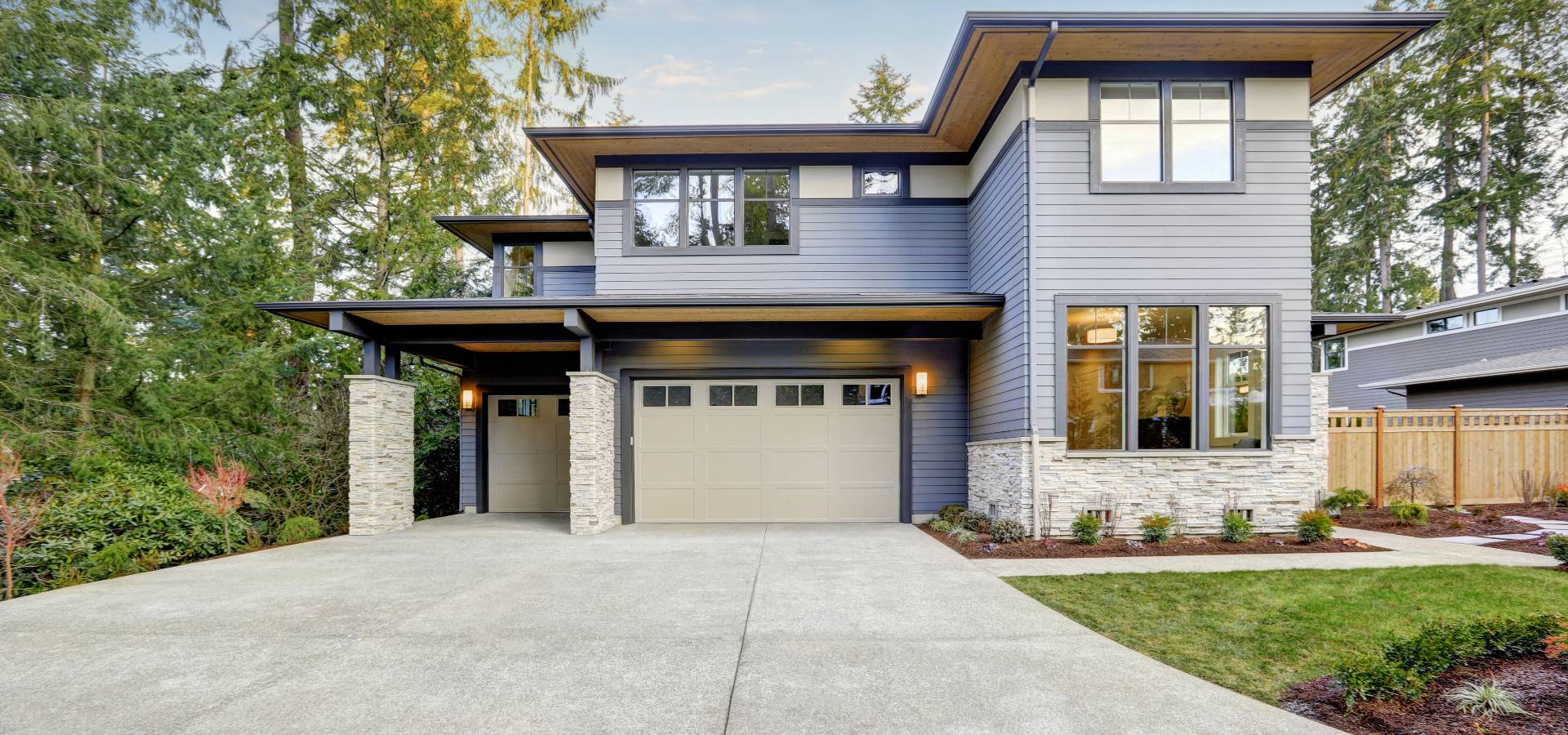 Luxurious new construction home in Bellevue, WA. Modern style home boasts two car garage framed by blue siding and natural stone wall trim